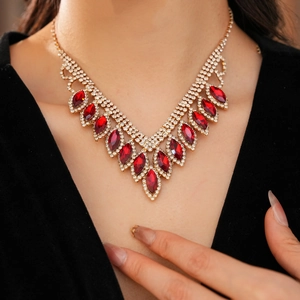 Close-up of elegant V-shaped gold necklace with red marquise stones on female model