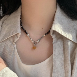 Collier de perles d'agate marron et pendentif en ambre jaune porté par un mannequin