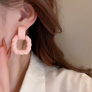 Pink acrylic twisted square drop earrings with striped rectangular studs on model
