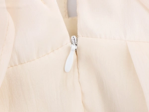 Close-up of invisible zipper detail on apricot floral dress with chiffon pleated texture