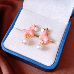 Close-up of 18K gold plated horse stud earrings with pink enamel and white pearl details