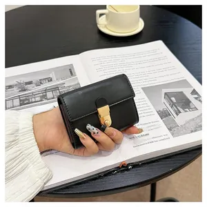 Close-up of a black textured leather wallet with a golden metal lock in a lifestyle setting