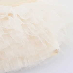 Primo piano di minigonna in tulle beige con pieghe a strati e trama delicata del tessuto