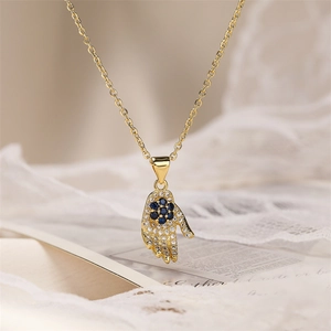 Macro detail of gold plated Hamsa pendant with sparkling blue and clear zircons