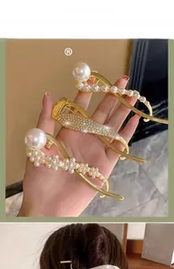 Detailed view of elegant gold hair clips with white pearls and rhinestones