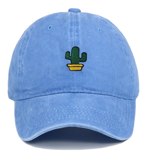 Detail shot of green cactus embroidery on a washed blue cotton baseball cap