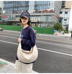 Off-white crescent-shaped oxford bag shown in a street-style urban commuting scene