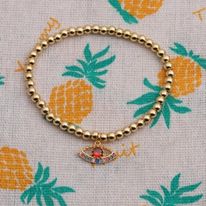 Macro detail of gold beaded bracelet featuring a colorful zircon inlaid evil eye pendant