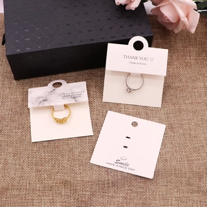 Golden and silver rings on marble and white display cards with floral and linen accents