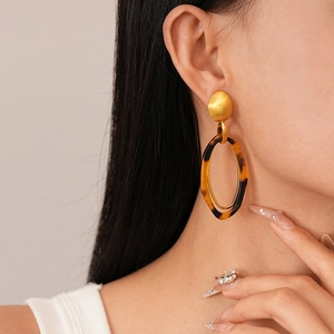 Close-up of vintage leopard resin hoop earrings with matte gold studs on a female model