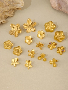Macro detail of gold flower stud earrings with brushed metal finish and colorful gemstones