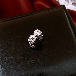 Detailed view of silver H-shaped ring with sparkling zircons on black leather display