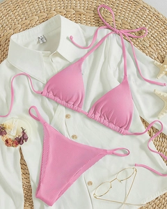Close-up of pink ribbed bikini set with tie-up straps and beach accessories
