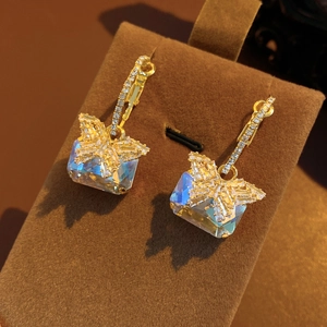 Nahaufnahme der goldenen Schmetterlingsohrringe mit Kristallen und blauem Opalstein