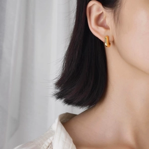 Minimalist gold titanium steel J-shaped earrings with polished finish on model