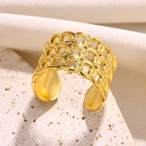 Macro shot of gold wide hollow chain ring on beige stone base with soft lighting