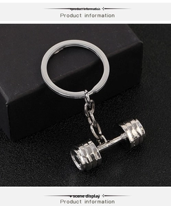 Detail shot of silver dumbbell keychain on black textured background with gift box