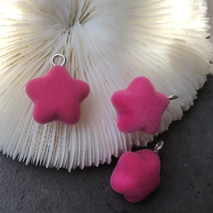 Close-up of three bright pink flocked star charms with silver metal rings for DIY crafts