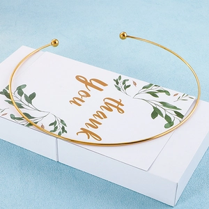 Detailed view of a golden minimalist open collar necklace on a gift card and blue background