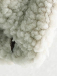 Close-up of soft white sherpa fleece fabric showing curly wool texture and soft pile