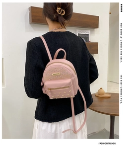 Detail of pink mini backpack with gold rivets and earphone hole on wooden stand