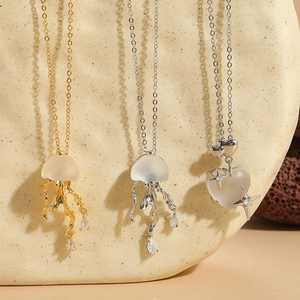 Macro detail of 14K gold plated jellyfish and heart pendants with frosted texture