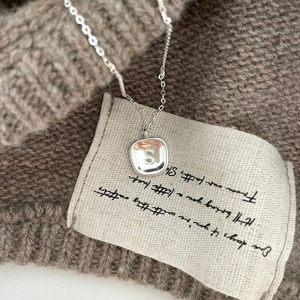 925 sterling silver S letter pendant necklace displayed on a dark knitted sweater background