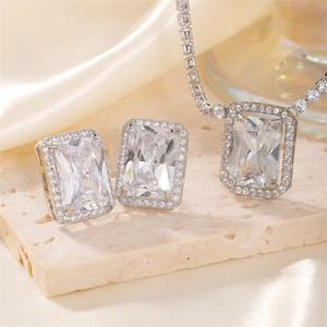 Elegant emerald-cut silver jewelry set with necklace and earrings on marble stone