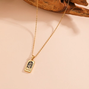 Close-up of golden tarot necklace with moon and star design on a pink background
