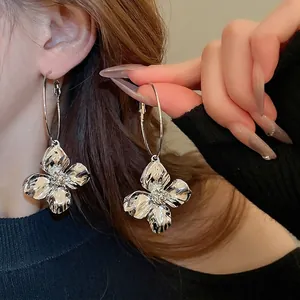 Orecchini a cerchio con fiori metallici argentati mostrati su una modella elegante
