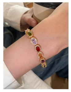 Detailed shot of gold bracelet featuring colorful oval stones and zircon halo on wrist