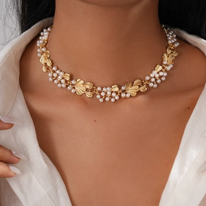 Detailed view of vintage gold leaf choker with white pearls on a model's neck