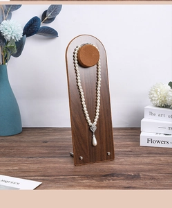 Arch-shaped walnut wood jewelry display stand with a pearl necklace on a velvet mount