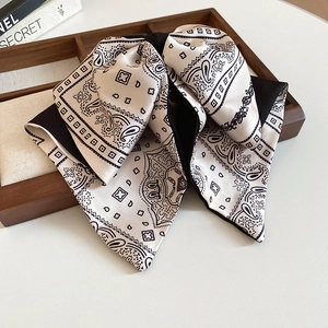 Detail of satin paisley bow hair claw with high-gloss texture on a wooden tray