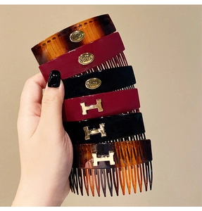 Close-up of tortoise shell and resin hair side combs with gold H letter metallic detail