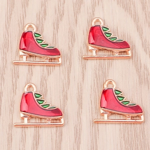 Detailed view of four red ice skate charms with green accents and gold enamel finish