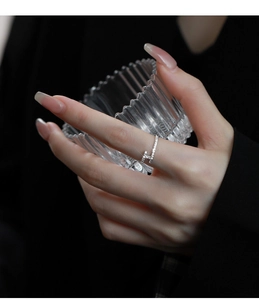 Close-up of silver crisscross ring with H-letter pavé zircons worn on hand