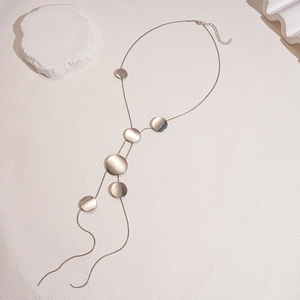 Minimalist long champagne gold tassel necklace with flat metal discs and sleek chain