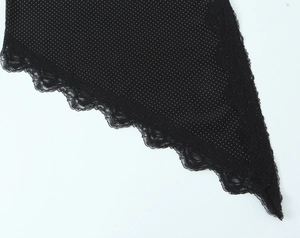Detail van zwarte polkadotstof met delicate kantafwerking op de asymmetrische camisole-top