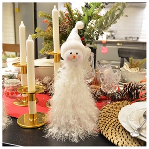 Detailed view of a plush white snowman Christmas tree hat on a festive dining table decor
