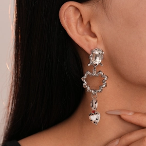 Macro shot of silver heart drop earring with rhinestone stud and marble patterned bead