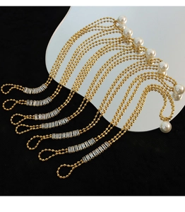 Detailed macro of gold beaded chain with white pearl and rectangular crystals