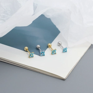 Macro shot of turquoise flower cartilage studs in gold and silver plating with zircon