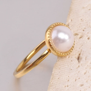 Detail of 10mm white pearl set in gold stainless steel ring with beaded texture edge