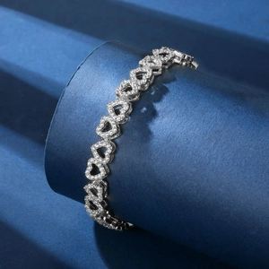 Macro shot of silver heart-shaped chain links with white cubic zirconia on a blue base