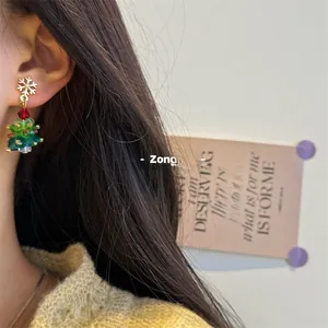 Close-up of beaded Christmas tree earrings featuring colorful crystals and golden snowflakes