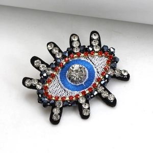 Evil eye embroidered brooch with blue crystals and beads on a clean white background
