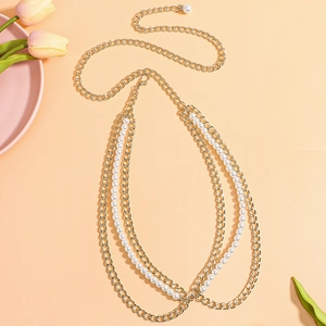 Detail of layered gold metal chain and white pearl body belt with elegant tulips