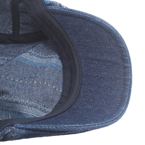 Detailed macro view of the inner stitching and blue striped lining of denim beret hat