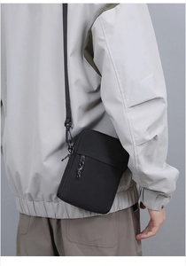 Rear view of a black nylon crossbody bag featuring adjustable straps and zipper detail